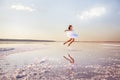 Young girl ballerina makes jumps in the water of a salt lake.