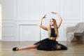 Young girl - ballet dancer in black tutu doing exercises and practice stretching leg up Royalty Free Stock Photo