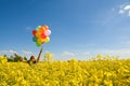 Young girl with balloons on canola field. Royalty Free Stock Photo