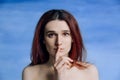 A young girl, with bare shoulders pressed her finger to his lips in gesture silently and looks to the side A person expresses Royalty Free Stock Photo