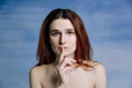 A young girl, with bare shoulders pressed her finger to his lips in gesture silently. A person expresses anxiety. Royalty Free Stock Photo