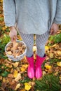 A young girl with a basket of mushrooms is standing in pink rubber boots Royalty Free Stock Photo