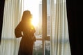 Young girl in bathrobe opens window transparent curtains in apartment