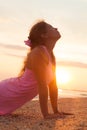 Young girl on beach at sunrise doing yoga exercise Royalty Free Stock Photo