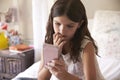 Young Girl In Bedroom Worried By Bullying Text Message