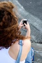 Young girl from behind holding cellphone and texting Royalty Free Stock Photo