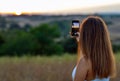 Young Girl taking photo of Sunset with her Smartphone Royalty Free Stock Photo