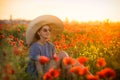 Young girl in a big hat sitting on a poppy field in sunset Royalty Free Stock Photo