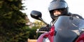 a young girl biker in a helmet and a moto suit, riding a red motorcycle