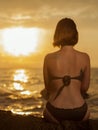 Young girl in bikini sitting on a rock on a seaside. Concept of vacation travel destination Royalty Free Stock Photo