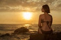 Young girl in bikini sitting on a rock on a seaside. Royalty Free Stock Photo