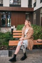 A young girl with a bionic prosthesis sits on a bench at the house.