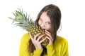 Young girl bites into a large ripe pineapple. Royalty Free Stock Photo