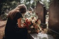 A young girl in a black dress with bouquets in her hands kneels at a granite tombstone and cries. Mourning for a loved one