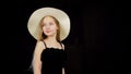 Young girl in black dress and white hat. Close up view, beautiful young model posing in evening dress and a hat, looking Royalty Free Stock Photo