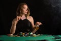 A young girl in a black evening dress plays poker in a casino. on a black background, horizontal photo Royalty Free Stock Photo