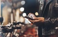 Young girl in black leather jacket using smartphone on background illumination glow bokeh light in night atmospheric city Royalty Free Stock Photo