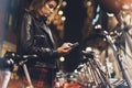 Young girl in black leather jacket using smartphone on background illumination glow bokeh light in night atmospheric city Royalty Free Stock Photo
