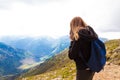 Young girl in a black sweater and leggings stands in the mountains and photographs the nature of beauty. Travel and