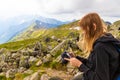 Young girl in a black sweater and leggings stands in the mountains and photographs the nature of beauty.