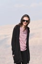 A young girl in a black sweatshirt and sunglasses on the background of rocks on the mountainside near the fortress of Al Karak in Royalty Free Stock Photo