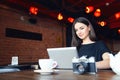 Young girl bloger freelancer photographer working on laptop in cafe Royalty Free Stock Photo