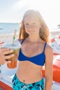 A young girl with blonde hair of European appearance, a teenager holds a colored cold non-alcoholic cocktail in her hand against Royalty Free Stock Photo