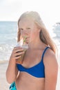 A young girl with blonde hair of European appearance, a teenager holds and drink a colored cold non-alcoholic cocktail in her hand Royalty Free Stock Photo
