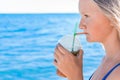 A young girl with blonde hair of European appearance, a teenager holds and drink a colored cold non-alcoholic cocktail in her hand Royalty Free Stock Photo