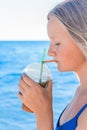 A young girl with blonde hair of European appearance, a teenager holds and drink a colored cold non-alcoholic cocktail in her hand Royalty Free Stock Photo