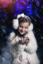 Young girl blows snowflakes in winter evening