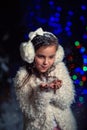 Young girl blows snowflakes in winter