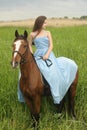 Young girl in a blue dress on a horse Royalty Free Stock Photo