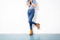 Young girl blue jeans brown shoes wall white. Royalty Free Stock Photo