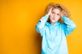 A young girl in a blue sweater stands against a bright background showing sadness. Emotions Royalty Free Stock Photo