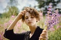 Young young girl with a bouquet of lupines in her hand against the background of blooming Ivan-tea