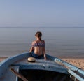 Young girl on the bow of a old wooden boat looking at the sea  sunset Royalty Free Stock Photo