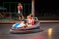 Young girl and boy driving a bumper car at a amusement park at night. Royalty Free Stock Photo