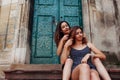 Young girl braids her best friend`s hair sitting on stairs outdoors. Happy women having fun Royalty Free Stock Photo