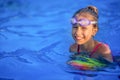 A girl in a bright bathing suit swims with an inflatable ball in a pool with clear water on a summer evening Royalty Free Stock Photo