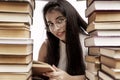 A young girl with a bunch of books sits at the table. Smiling brunette wearing glasses. Back to school. Knowledge and education. Royalty Free Stock Photo