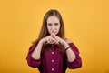 Young girl in burgundy bluse with bow showing a sign of silence Royalty Free Stock Photo