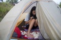 A young girl busy checking phone or playing game in a tend during camping activity on the hills. Royalty Free Stock Photo