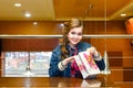 Young girl in a cafe opens a gift bag and smiling Royalty Free Stock Photo