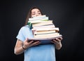 Young girl carrying heavy pile of books Royalty Free Stock Photo