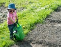 Young girl carrying a large green watering can as she helps in the vegetable garden Royalty Free Stock Photo