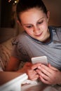 Young Girl Checking Text Messages Lying On Bed At Night Royalty Free Stock Photo