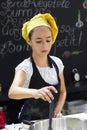 Young girl in a chef`s hat cooks in a large saucepan in a black Royalty Free Stock Photo