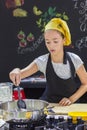 Young girl in a chef`s hat cooks in a large saucepan in a black Royalty Free Stock Photo