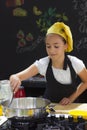Young girl in a chef`s hat cooks in a large saucepan in a black Royalty Free Stock Photo